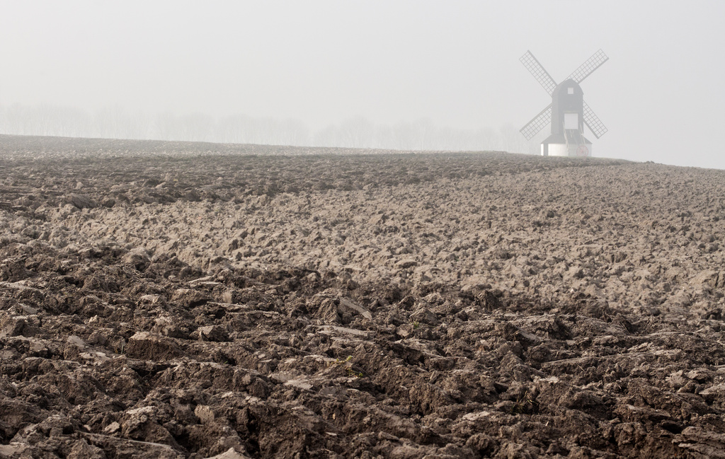 Ploughed field with misty mill by dulciknit