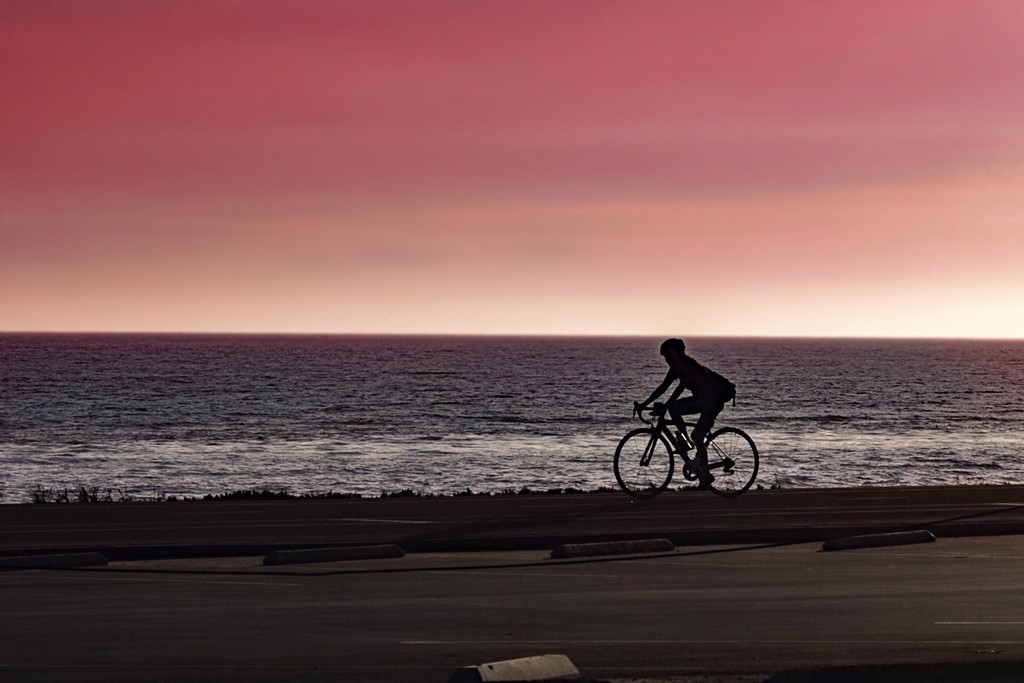 Biker along Malibu Beach at Sunset by jaybutterfield