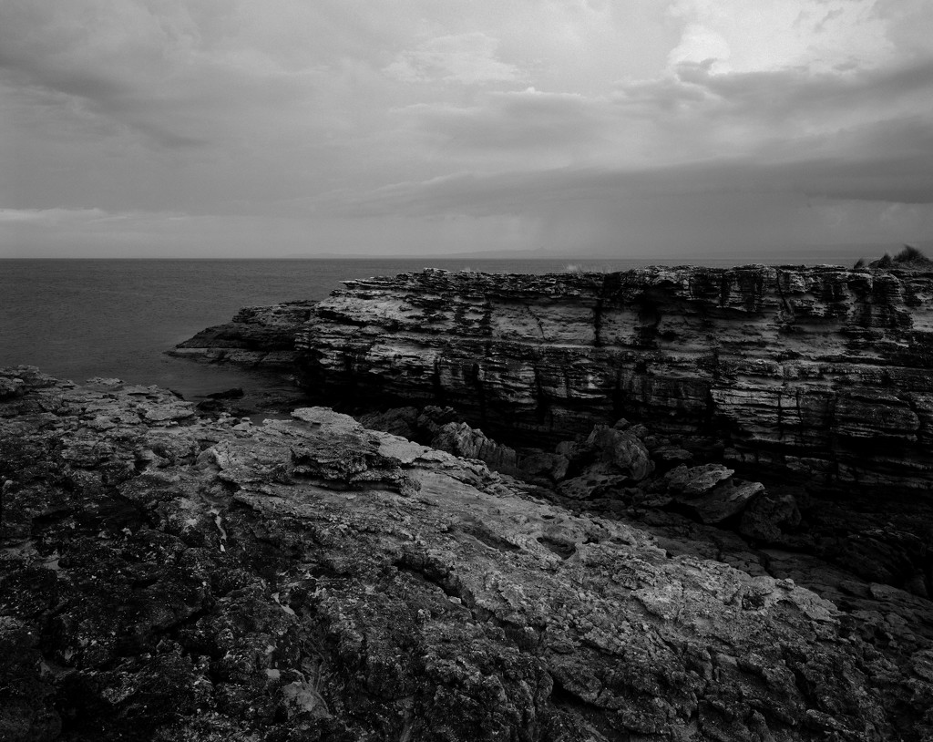 Rocky headland and distant clouds by peterdegraaff
