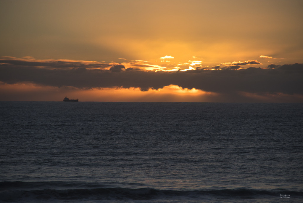 Sunset with cargo boat by dkbarnett