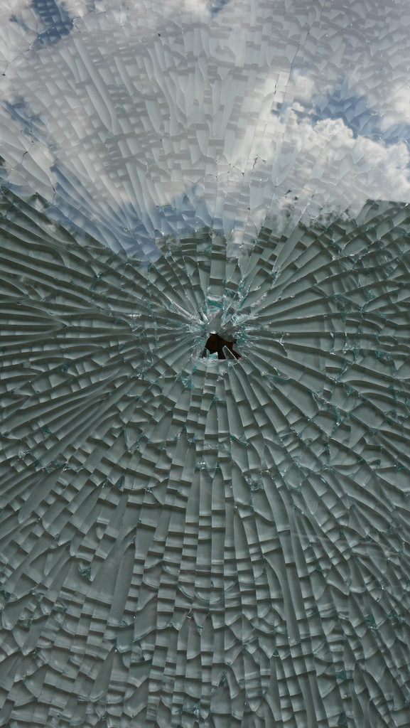 Photo of large glass panel window at  Atlanta nightclub, punctured by a bullet.  by swagman