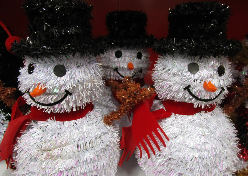 Smiling snowmen with red scarves by mittens