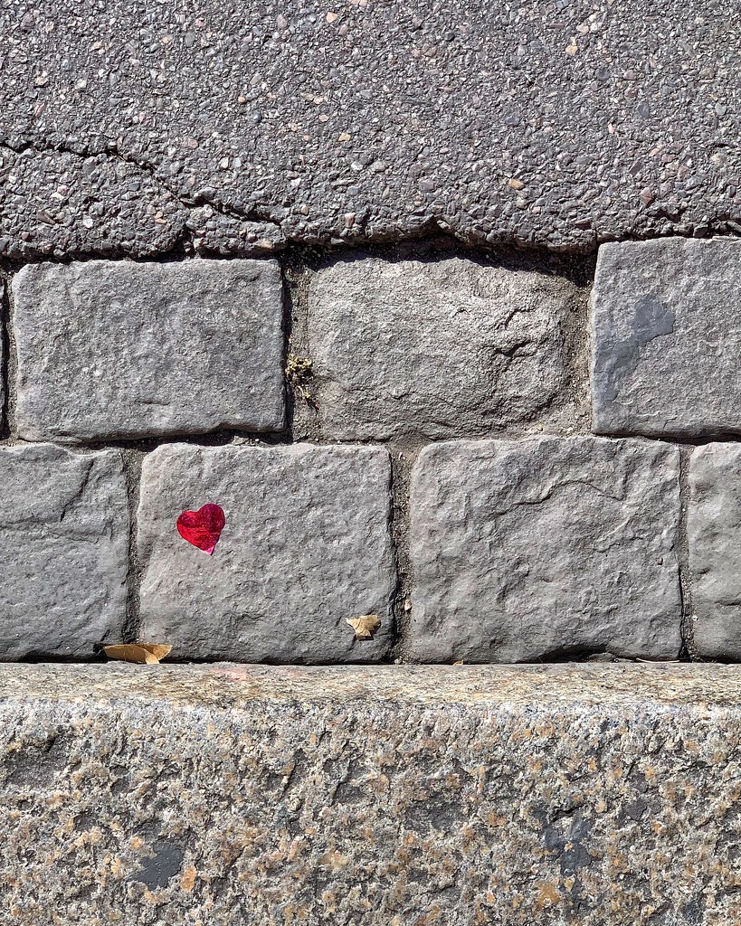 Tiny red heart on cobbled street.  by cocobella