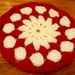 A red and cream crocheted flower coaster. by grace55