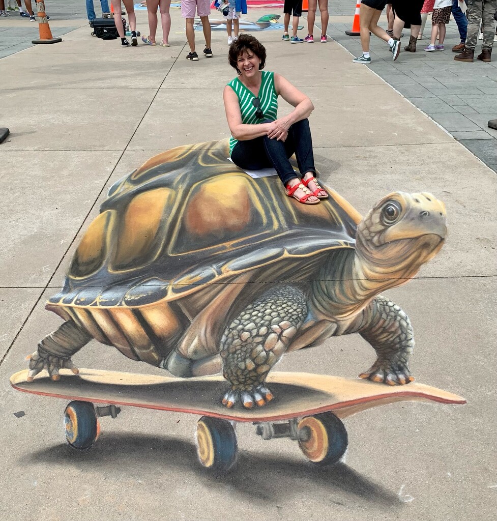 Lori riding a chalk art 3-D turtle!  by louannwarren