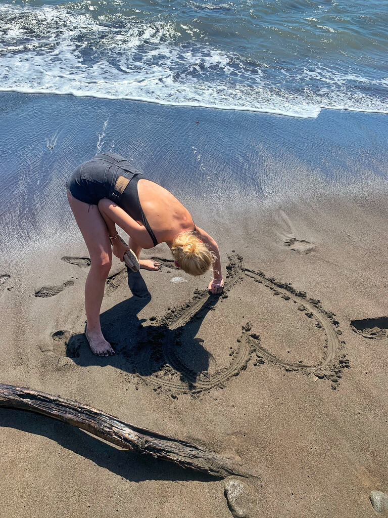 She draws heart on the sand.  by cocobella