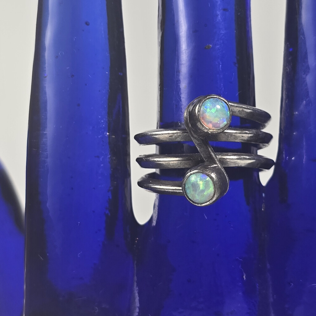 Opal and silver ring on blue glass hand, detail by peachfront