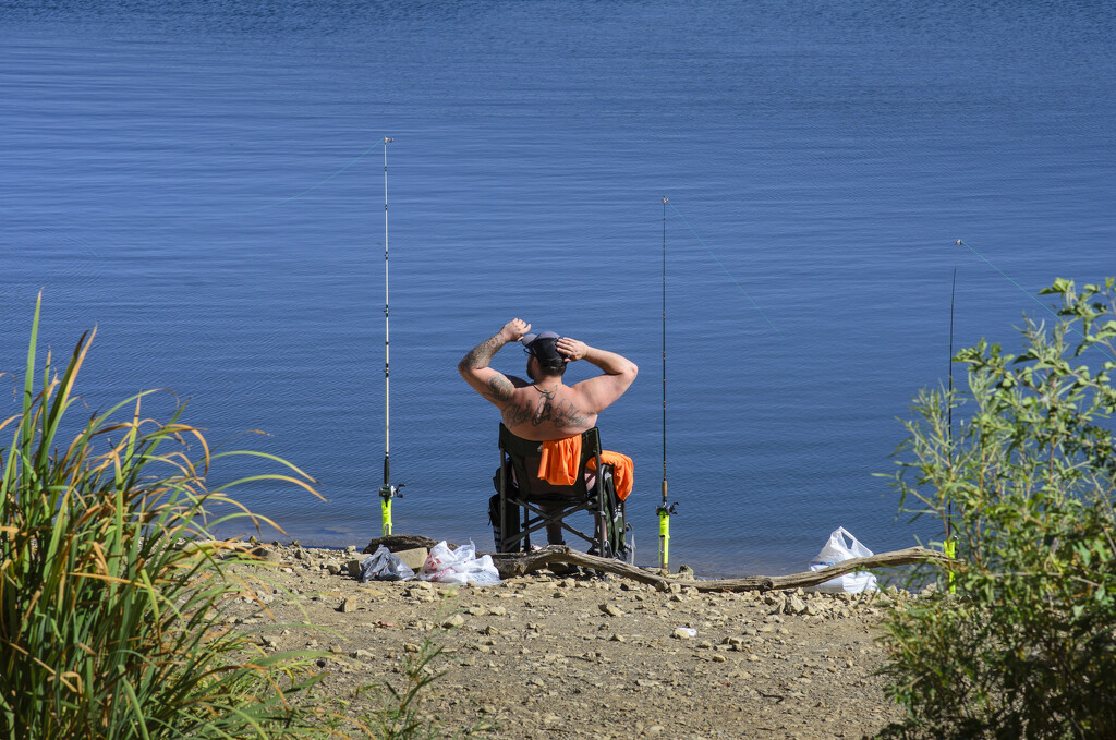 Fisherman takes a stretch on a slow day of fishing by ggshearron