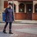 Woman looks at a commotion being caused down the street as she waits on the light to change
